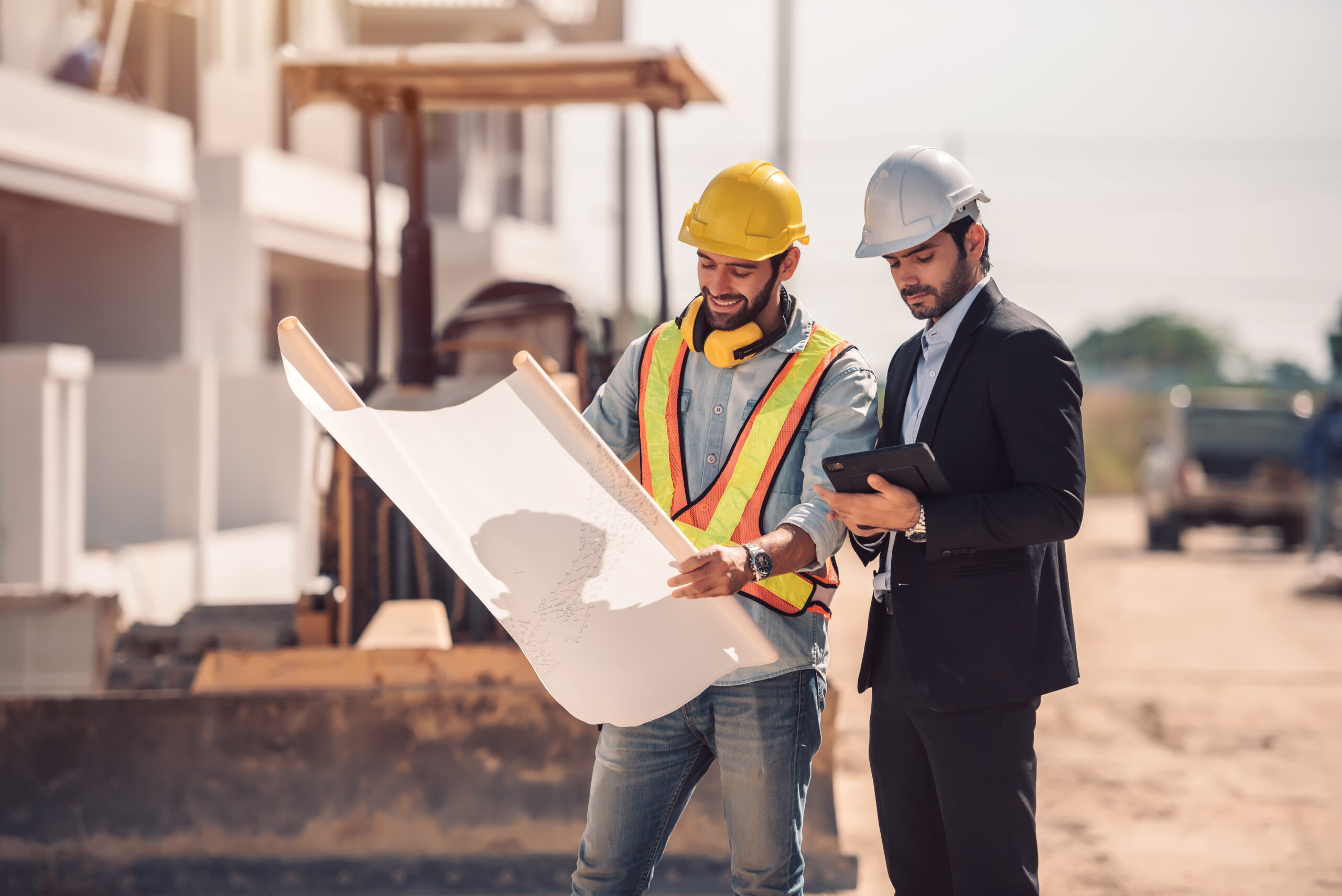 Civil engineer and construction worker manager holding digital tablet and blueprints , talking and planing about construction site.  Cooperation teamwork concept.